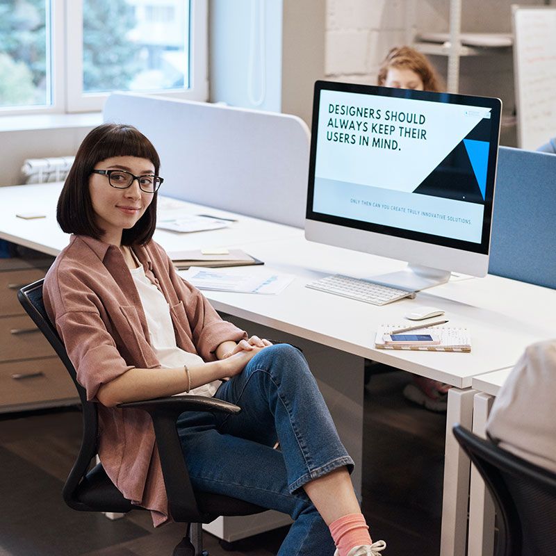 Frau sitzt gemütlich am Tisch vor Bildschirm