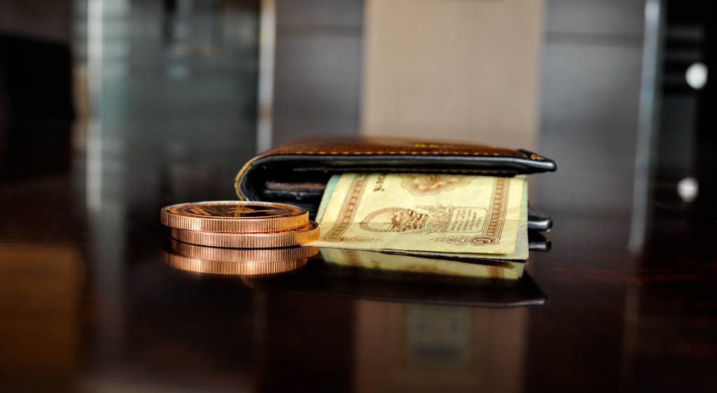 Arrangement of antique coins and banknotes beside a wallet, reflecting luxury finance.