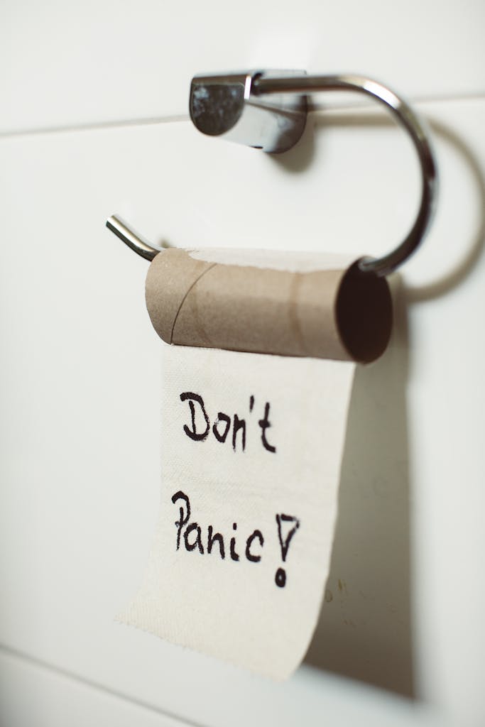 Close-up view of an empty toilet paper roll with a comforting "Don't Panic" message hanging on a holder.