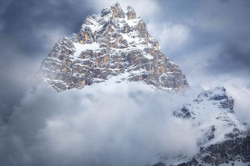 Majestic snow-covered peak in Cortina d'Ampezzo, Italy, surrounded by clouds.